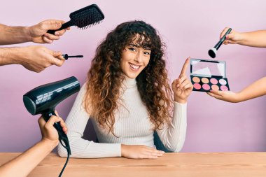 Masada elleri kozmetik ellerle oturan genç İspanyol kız bir fikir veya soruyla gülümsüyor ve mutlu bir yüzle işaret ediyor. 