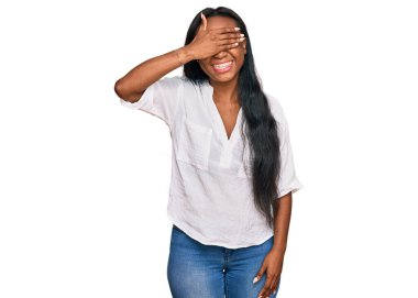 Gündelik kıyafetler giyen, gülümseyen ve gülen genç siyahi kadın şaşırtmak için gözlerini kapatıyor. kör kavram. 