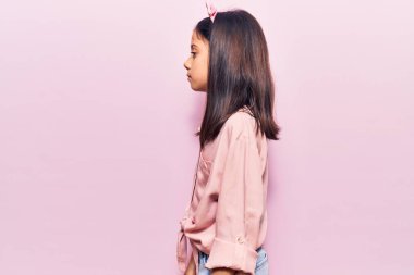 Güzel bir kız çocuğu günlük giysiler içinde, rahat bir görünüm takınıyor, doğal bir yüz ve kendine güvenen bir gülümsemeyle poz veriyor.. 