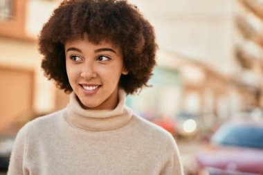 Genç İspanyol kız gülümseyerek şehirde mutlu mesut dikiliyor..