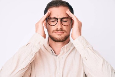 Genç yakışıklı adam günlük kıyafetler ve gözlük takıyor. Baş ağrısı, çaresiz ve stresli. Çünkü acı ve migren ağrısı var. Eller başının üstünde.. 
