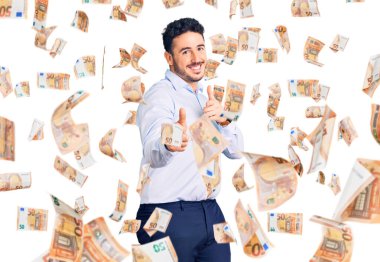 İş kıyafetleri giymiş genç İspanyol adam mutlu ve komik yüzüyle kamerayı işaret ediyor. iyi enerji ve titreşimler.