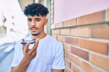 Genç Arap adam şehirdeki akıllı telefonu kullanarak sesli mesaj gönderiyor.