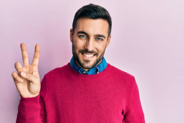 Gündelik kıyafetler giyen genç İspanyol adam kameraya bakıp zafer işareti yaparken parmaklarını gösteriyor. İki numara.. 