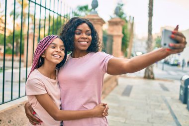 Afrika kökenli Amerikalı anne ve kızı, şehirdeki akıllı telefonların yanında birbirlerine sarılıp selfie çekiyorlar..
