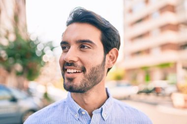 Genç İspanyol adam gülümseyerek şehirde mutlu bir şekilde yürüyor..