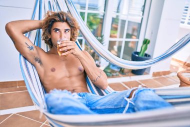 Genç İspanyol adam terasta hamakta uzanmış bira içerek rahatladı..