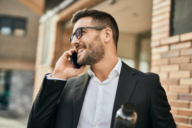 Genç İspanyol işadamı gülümsüyor. Şehirdeki akıllı telefondan mutlu bir şekilde konuşuyor..