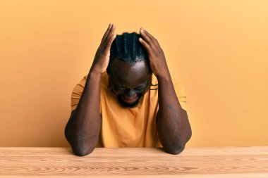 Yakışıklı, gündelik giysiler giyen genç bir adam. Masada oturuyor. Baş ağrısı çekiyor, çaresiz ve stresli. Eller başının üstünde.. 