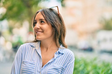 Genç İspanyol kadın gülümseyerek şehirde mutlu mesut dikiliyor..