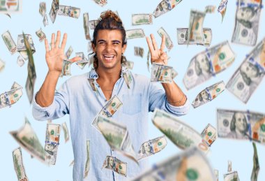 Yaz stili giyinmiş genç İspanyol adam 8 numarayı gösterip işaret ederken kendinden emin ve mutlu gülümsüyor..