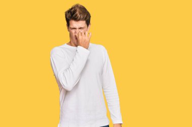 Beyaz bir süveter giyen yakışıklı beyaz bir adam pis ve iğrenç bir koku alıyor. Nefesini burnunda tutuyor. Kötü kokuyor. 