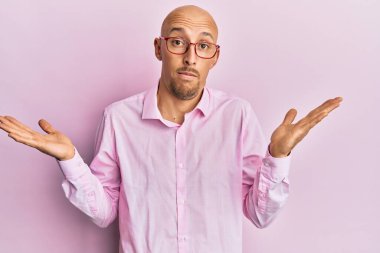 Sakallı, sıradan kıyafetler giyen, gözlüklü, kafası karışık, kolları açık, hiçbir fikri olmayan, şüpheli bir yüzü olan kel bir adam.. 