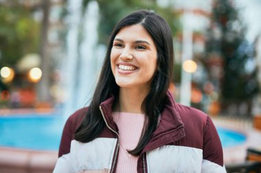 Genç İspanyol kız parkta mutlu bir şekilde gülümsüyor..