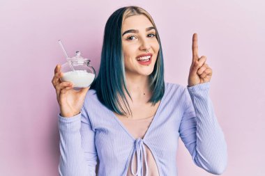 Genç, modern bir kız elinde şeker dolu bir kaseyle bir fikre şaşırmış ya da mutlu yüzle işaret eden bir soru sormuş. 