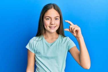 Güzel, esmer, beyaz tişört giyen, gülümseyen, kendine güvenen, el hareketi yapan, parmaklarıyla işaret yapan ve kameraya bakan bir kız. ölçüm kavramı. 