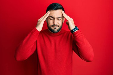 Latin asıllı genç bir adam elleri kafasında günlük kıyafetler giyiyor, stres yüzünden baş ağrısı çekiyor. migren ağrısı. 