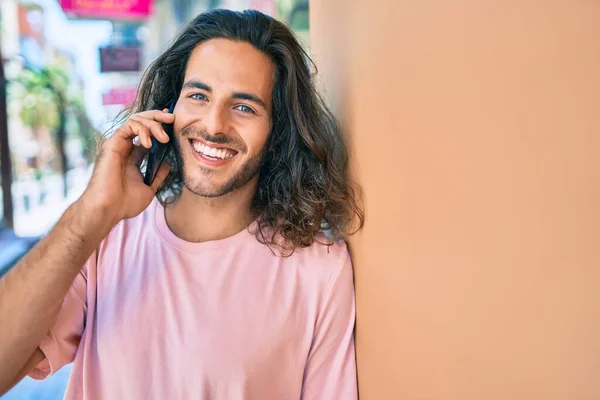 Joven Hombre Hispano Sonriendo Feliz Hablando Smartphone Apoyado Pared —  Fotos de Stock