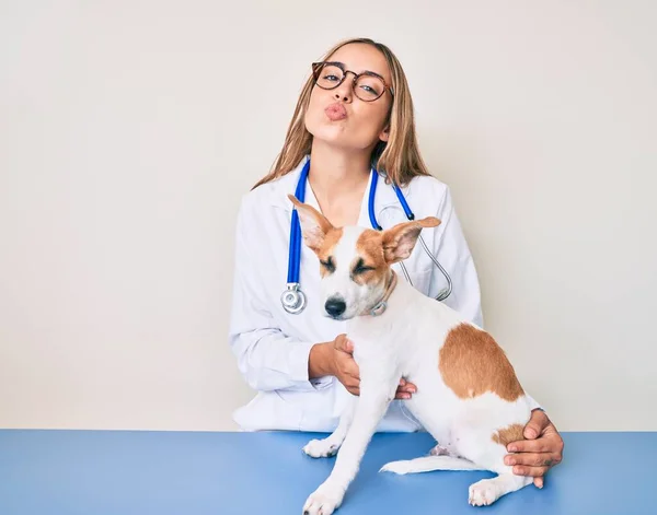 若い美しいブロンドの獣医師の女性が犬の健康をチェックしているカメラを見て キスが美しくセクシーさを吹いている 愛の表現 — ストック写真
