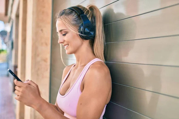 Jovem Loira Menina Esportiva Usando Smartphone Fones Ouvido Encostados Parede — Fotografia de Stock