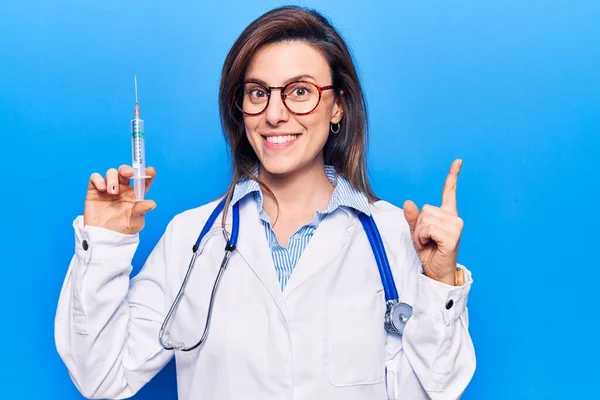 Młoda Piękna Kobieta Nosząca Stetoskop Lekarski Trzymająca Strzykawkę Uśmiechająca Się — Zdjęcie stockowe