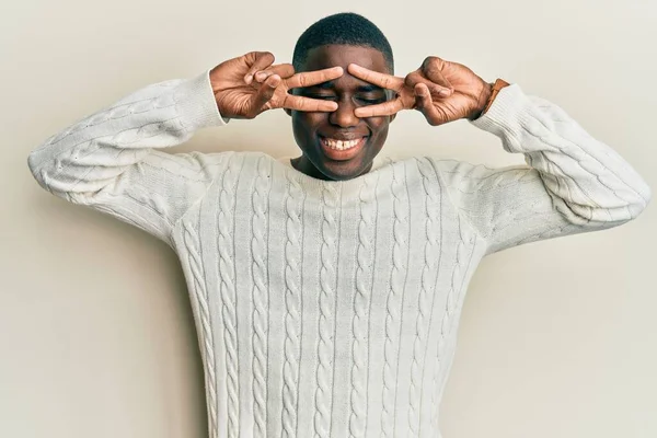 顔の上に指で平和のシンボルを行うカジュアルな服を着て若いアフリカ系アメリカ人の男 勝利を示す明るい笑顔 — ストック写真