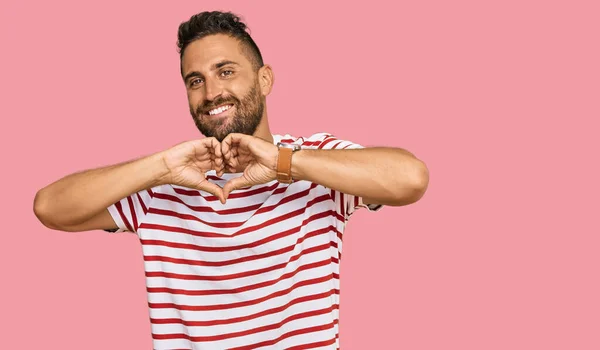 Pohledný Muž Vousy Pruhované Tričko Úsměvem Lásce Ukazuje Symbol Srdce — Stock fotografie