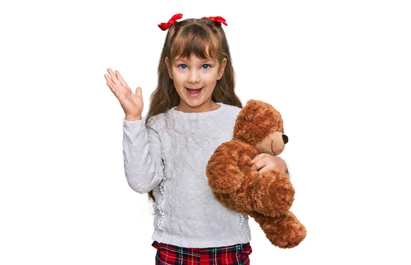 小高加索女孩抱着玩具熊毛绒玩具动物 开心地微笑着庆祝胜利 用高举双手庆祝胜利 — 图库照片