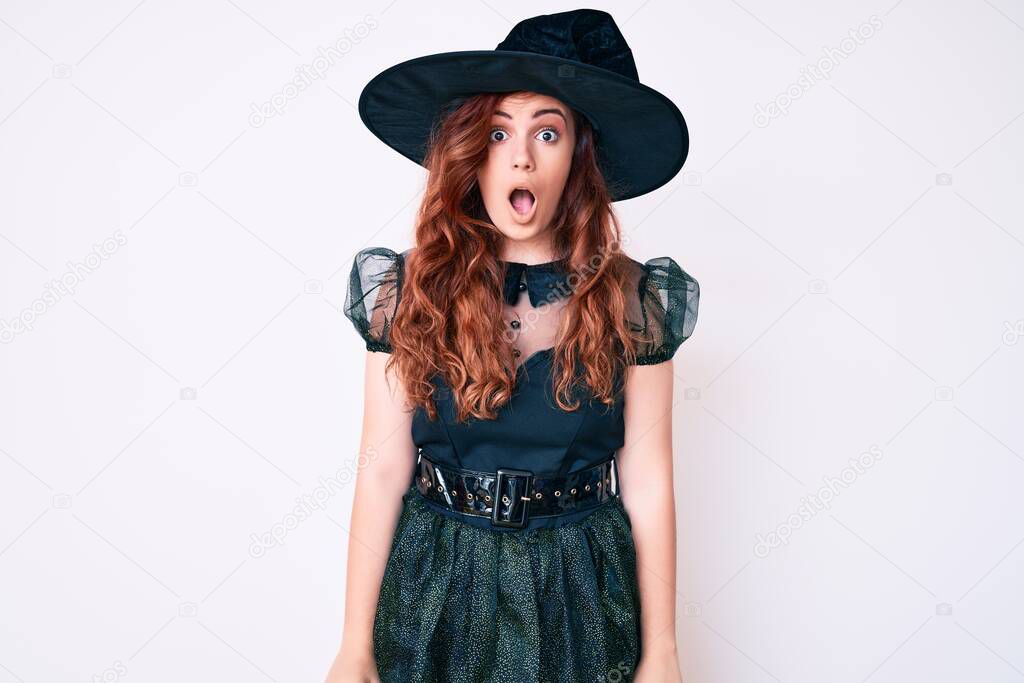 Young beautiful woman wearing witch halloween costume afraid and shocked with surprise and amazed expression, fear and excited face. 