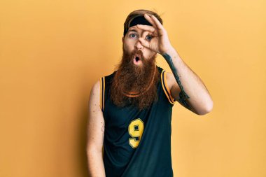 Uzun sakallı, basketbol forması giyen, iyi bir jest yapan, şaşkın suratlı, parmaklarından bakan kızıl saçlı bir adam. İnançsız ifade. 