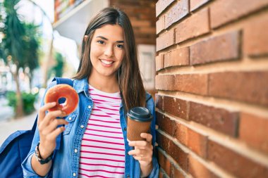 Genç İspanyol öğrenci gülümseyerek şehirde kahvaltı yapıyor..