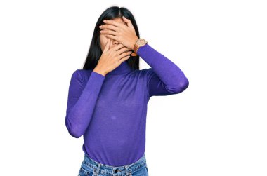 Güzel, genç Asyalı kadın sıradan kıyafetler giyip gözlerini ve ağzını elleriyle kapatmış, şaşırmış ve şok olmuş. duygu gizleme 