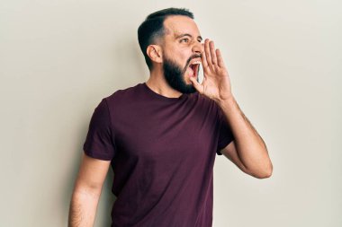 Sakallı, sıradan tişörtlü genç bir adam el ele tutuşup bağırıyor ve bağırıyordu. iletişim konsepti. 