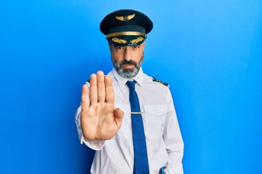 Sakallı, gri saçlı, uçak pilotu üniforması giyen orta yaşlı bir adam avucunun içi gibi şarkı söylemeyi kesiyor. Yüzünde olumsuz ve ciddi bir jest olan uyarı ifadesi. 