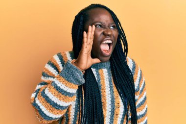 Saçları örgülü genç siyahi bir kadın sıradan bir kazak giyip el ele tutuşarak bağırıyor ve çığlık atıyordu. iletişim konsepti. 