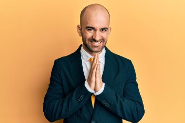 Genç İspanyol takım elbiseli ve kravatlı adam elleriyle dua ederek af diliyor kendinden emin bir şekilde gülümsüyor.. 