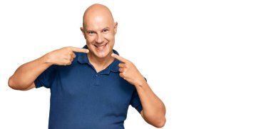 Orta yaşlı, kel, günlük kıyafetler giyen neşeli bir şekilde gülümseyen, parmakları, dişleri ve ağzı olan bir adam. diş sağlığı kavramı. 