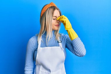 Güzel sarışın kadın daha temiz önlük giyiyor ve eldivenler giyiyor. Burun ve gözler sürtünüyor, yorgunluk ve baş ağrısı hissediyor. Stres ve hüsran kavramı. 