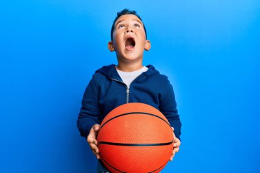 Küçük İspanyol çocuk basketbol topunu elinde tutuyor kızgın ve kızgın bağırıyor sinirli ve öfkeli, öfkeyle bağırıyor.. 