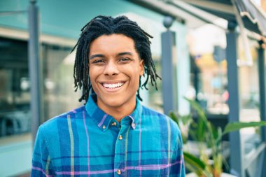 Genç Afrikalı Amerikalı adam gülümsüyor. Şehrin caddesinde kameraya bakıyor..