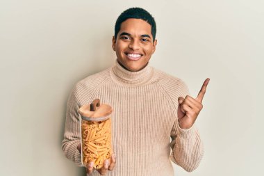 Genç, yakışıklı İspanyol adam elinde makarna dolu kavanozla mutlu bir şekilde gülümsüyor. 