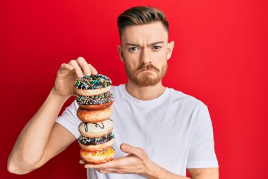 Genç kızıl saçlı adam elinde lezzetli renkli çörekler tutuyor. Depresyonda ve endişe içinde. Kızgın ve korkmuş. hüzünlü ifade. 