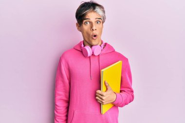 Genç İspanyol adam elinde kulaklıkla kitap tutuyor. Korkmuş ve ağzı açık bir şekilde şaşırmış, inançsız bir yüz. 