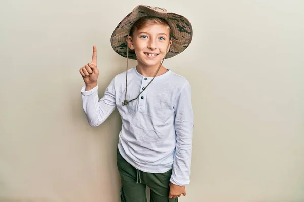 小さな白人少年探検家の帽子をかぶって笑顔アイデアや質問を指さして指を上に幸せな顔 第1位 — ストック写真