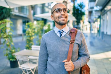 Genç Afrikalı Amerikalı iş adamı gülümseyerek şehirde mutlu bir şekilde yürüyor..