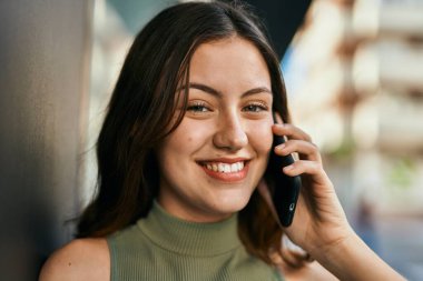 Beyaz kız gülümsüyor. Şehirdeki akıllı telefondan konuşuyor..