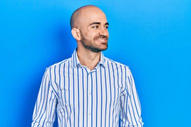 Zarif kıyafetler giyen genç kel bir adam yan bakmak için, rahat profil pozu doğal bir yüz ve kendinden emin bir gülümseme ile. 