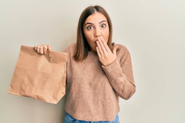 Elinde paket kağıdı tutan genç ve güzel bir kadın. Ağzını eliyle kapatıyor. Şok olmuş ve hata yapmaktan korkuyor. şaşırmış ifade 