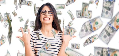 Esmer, sıradan kıyafetler ve gözlük takan çılgın bir ifadeyle bağıran genç kız elleri havada rock sembolü yapıyor. Müzik yıldızı. ağır kavram.