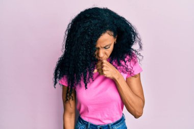 Orta yaşlı Afro-Amerikalı kadın günlük giysiler giyiyor kendini iyi hissetmiyor ve soğuk algınlığı veya bronşitin belirtisi olarak öksürüyor. sağlık hizmeti kavramı. 